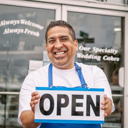 Store owner holding an open sign.